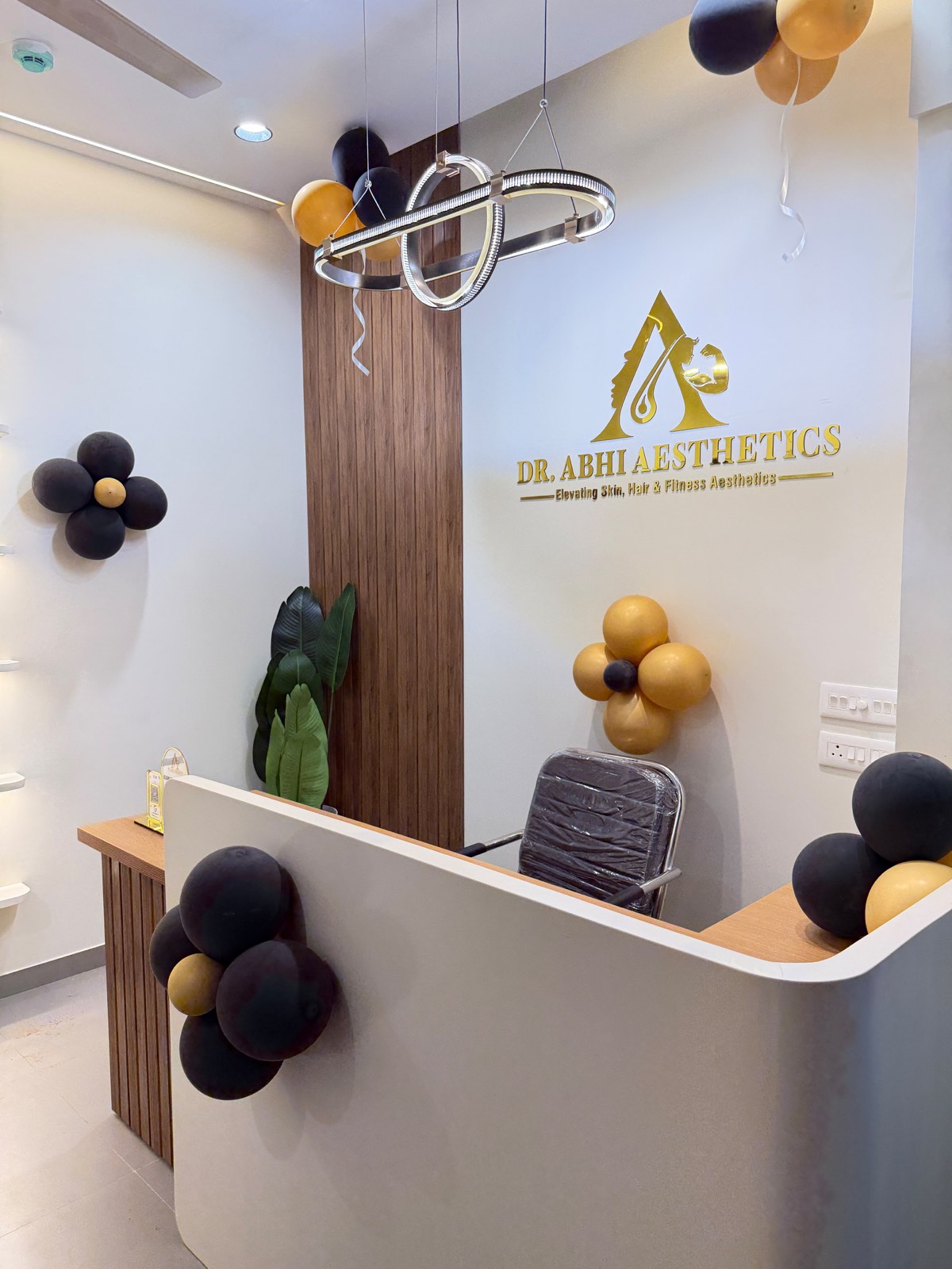 The reception desk at Dr. Abhi Aesthetics, with the clinic's gold monogram on the wall behind it.