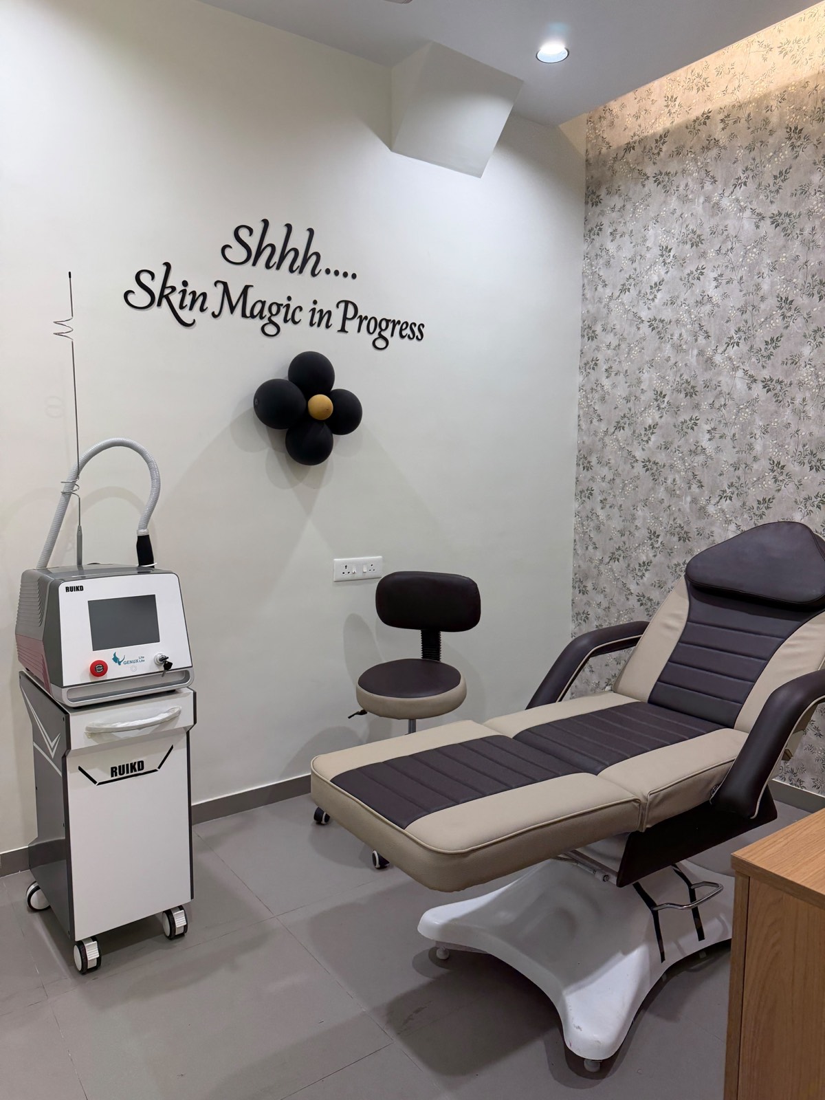 A treatment room at Dr. Abhi Aesthetics with a laser system beside a reclining treatment chair.